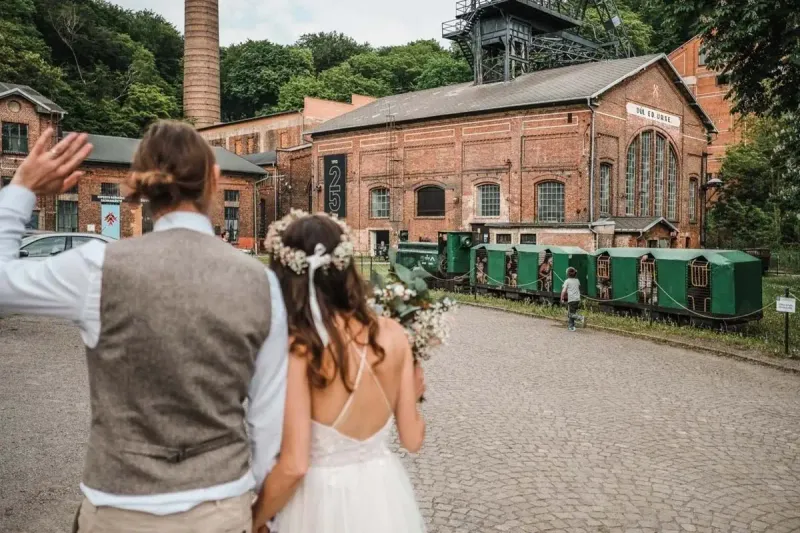 Svatba na Landeku - Pár s historickými vagóny důlního muzea v pozadí.