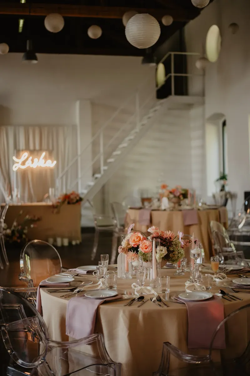 Svatba na Landeku - Interiér sálu s neonem Láska a elegantními ghost stoličkami.